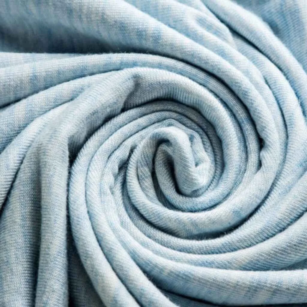A close-up shot of light blue bamboo fabric elegantly rolled, highlighting its soft texture.