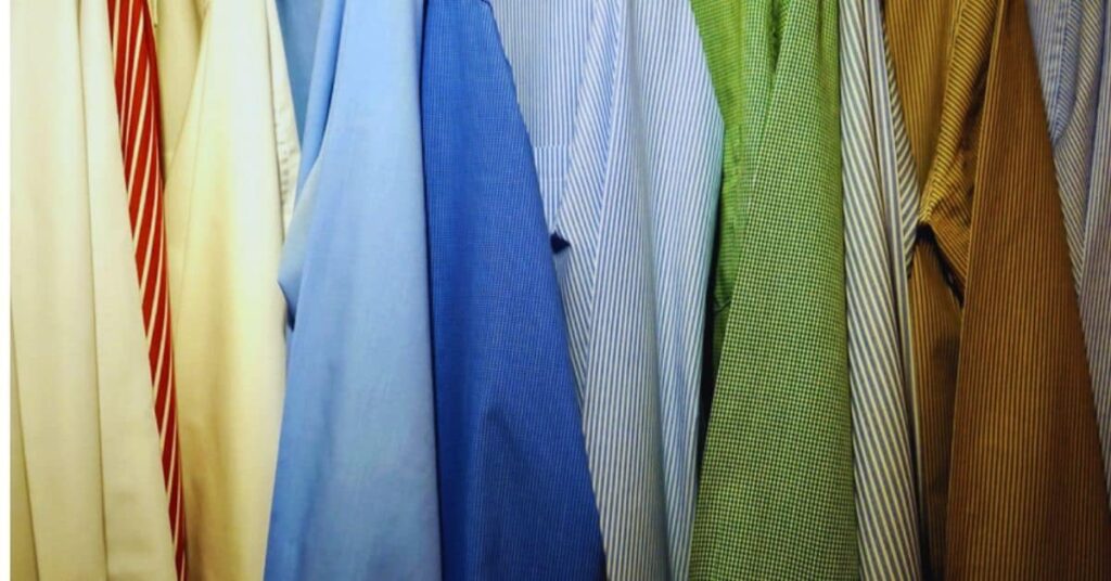 Colorful poplin fabric shirts hanging on a rack, showcasing various patterns and textures.
