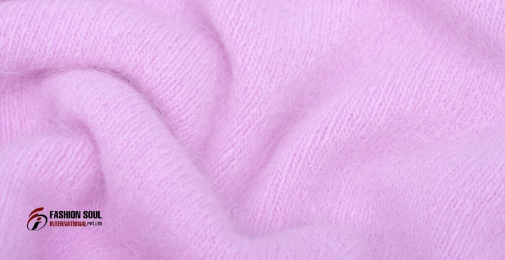 Close-up of soft, pink Angora wool fabric with a fluffy texture, featuring a subtle knit pattern.