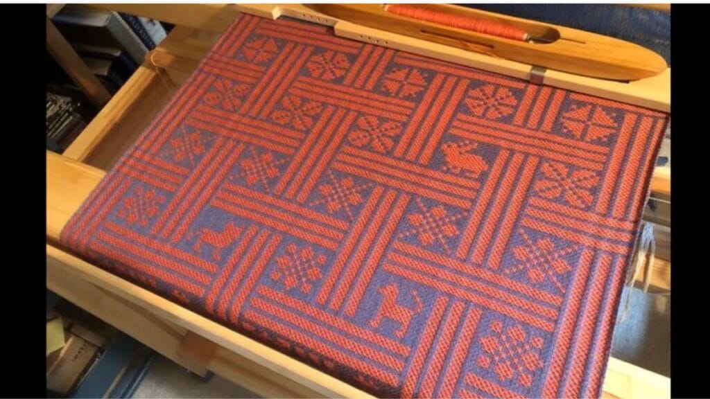 A detailed textile weave pattern showing damask fabric with intricate, reversible floral and geometric motifs, created on a loom with white-on-white contrast.