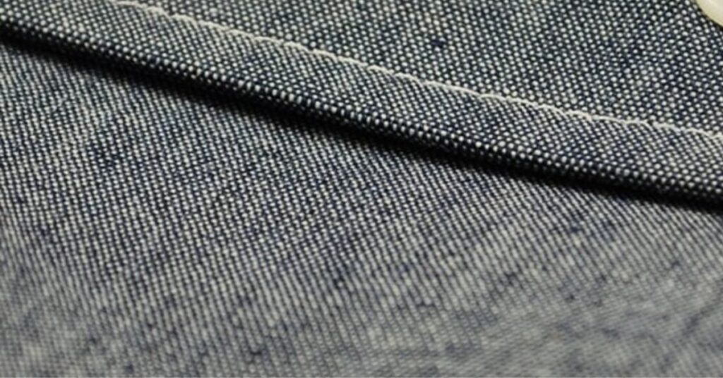 Close-up view of chambray fabric showing its fine weave, soft texture, and signature blue and white color contrast.