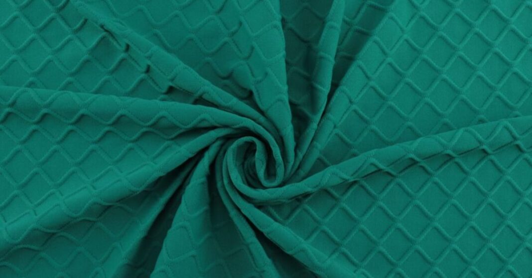 Close-up of green elastane fabric with a textured, diamond-shaped pattern, showcasing its stretch and flexibility.