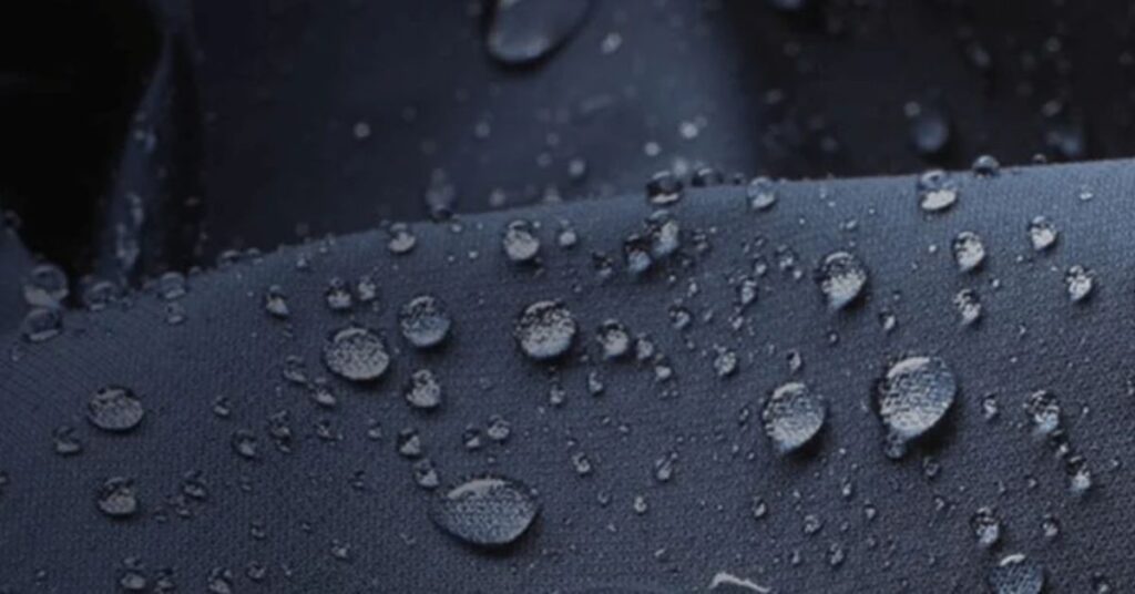 Close-up of waterproof Gore-Tex fabric with water droplets beading up on the surface, highlighting its water-resistant properties.