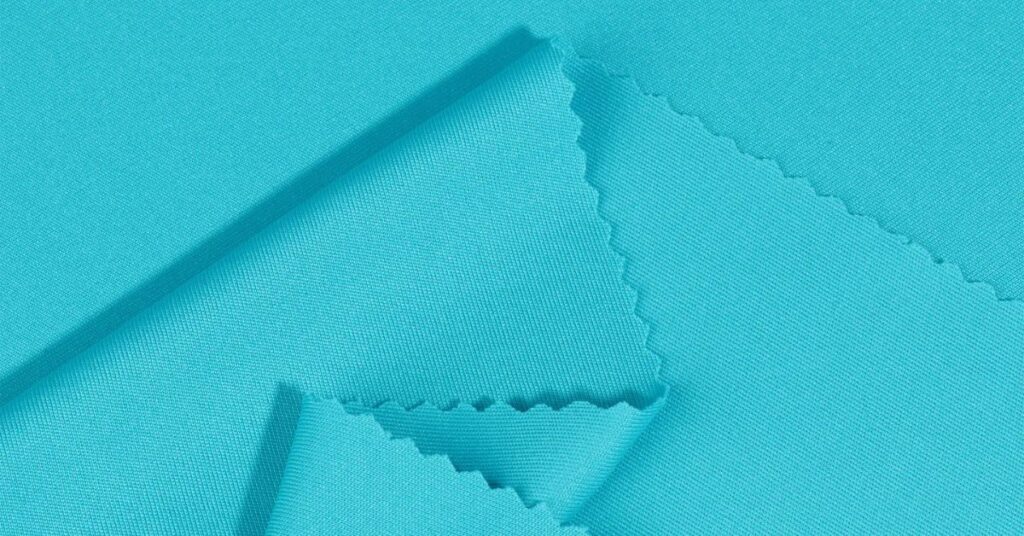 Close-up of turquoise interlock fabric showcasing its smooth, double-knit texture and fine finish.