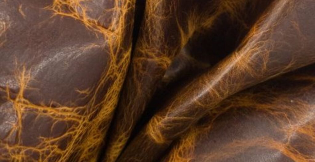 pull up leather with a distressed, crackled texture. Close-up of folded pull up leather with gold veining.