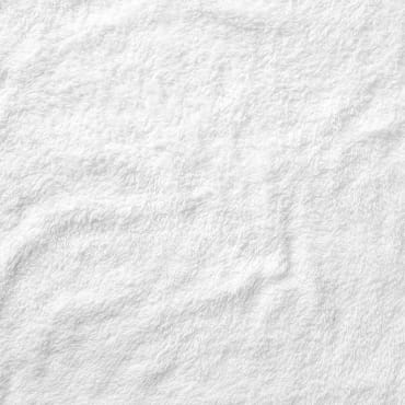 A plain white cotton fabric with subtle textured wrinkles, showing a clean and bright appearance.