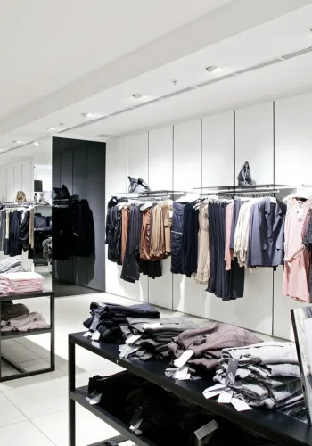 A modern clothing store interior featuring clothing displays on racks and folded items on tables.