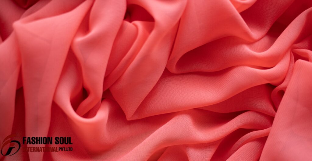 A close-up view of soft, coral chiffon fabric with flowing folds and a sheer texture. Smart & safely