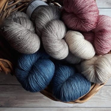 Balls of colorful cotton yarn arranged in a basket, ready for knitting or crochet.
