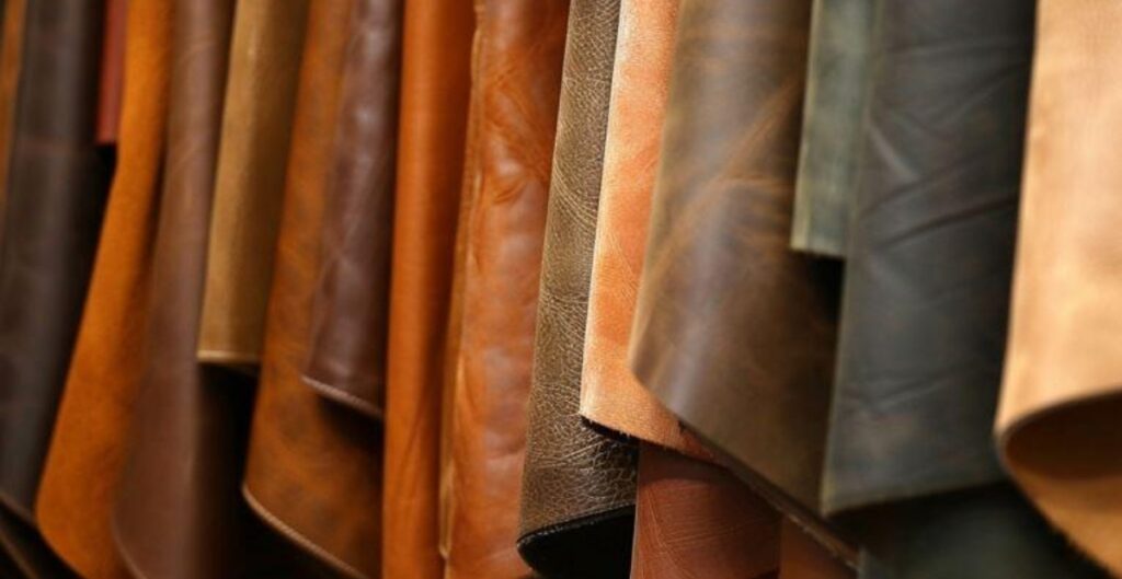 Various pieces of cowhide leather in different colors and textures hanging in a display.