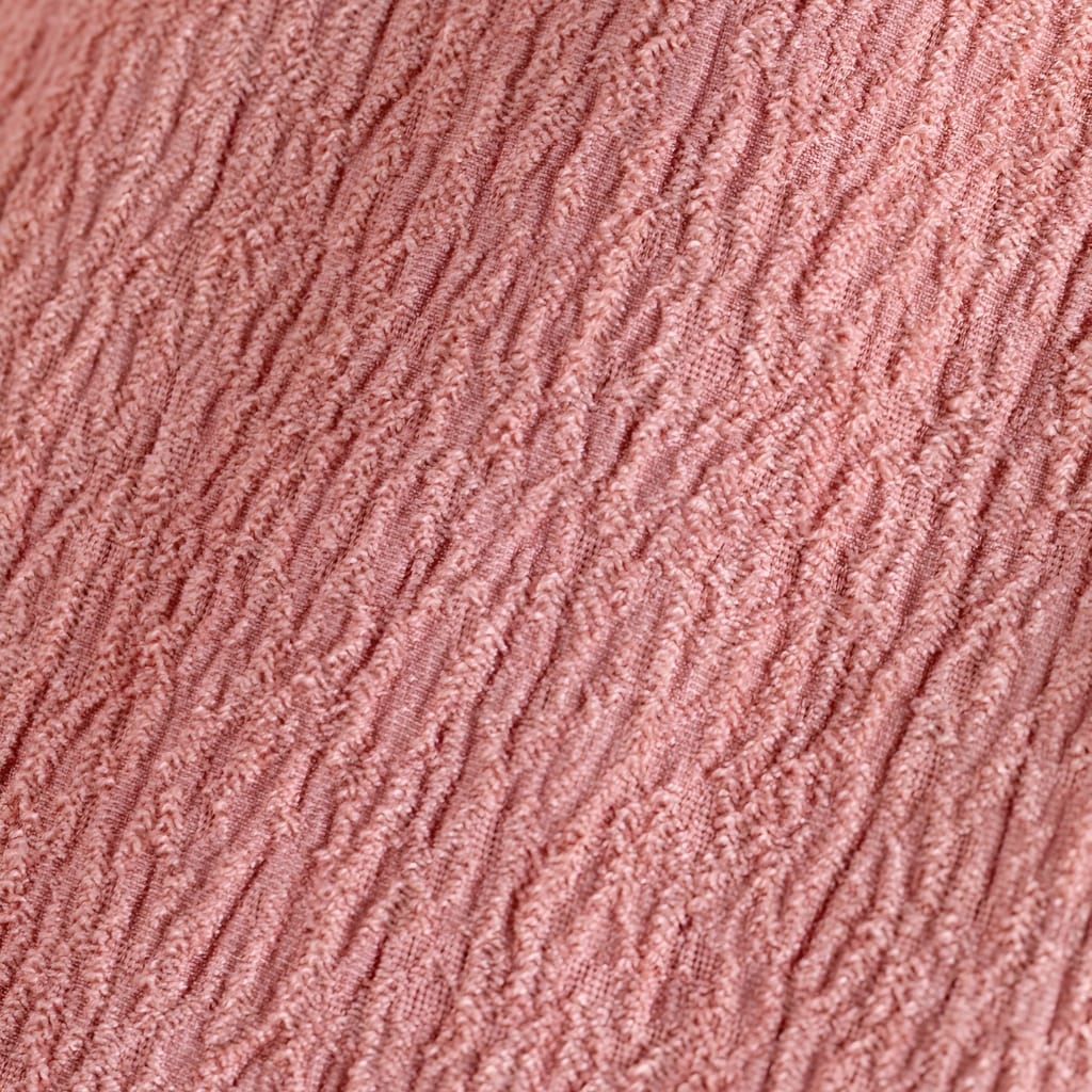 A close-up image of a textured fabric in a soft pink color, showing detailed thread patterns and a ribbed surface.