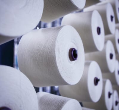 Rolls of cotton yarn stacked in a textile factory.