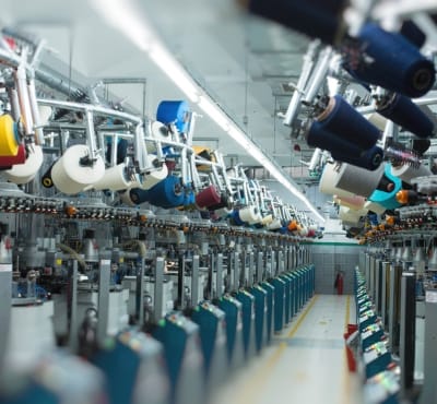 Industrial textile machinery with spools of cotton thread, showcasing the production process in a cotton manufacturing facility.