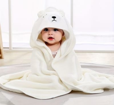 Adorable baby wrapped in a soft, white hooded blanket resembling a bear, with the hood featuring bear ears and a cute face.