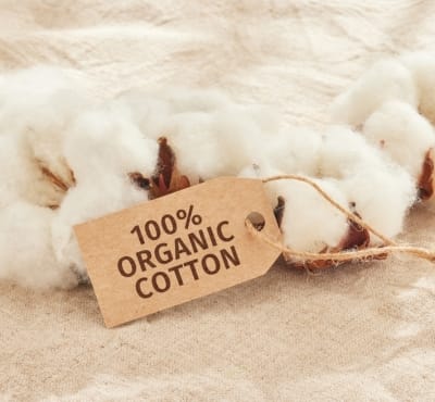 A close-up image of cotton bolls with a tag that reads "100% Organic Cotton." Is Cotton Soft