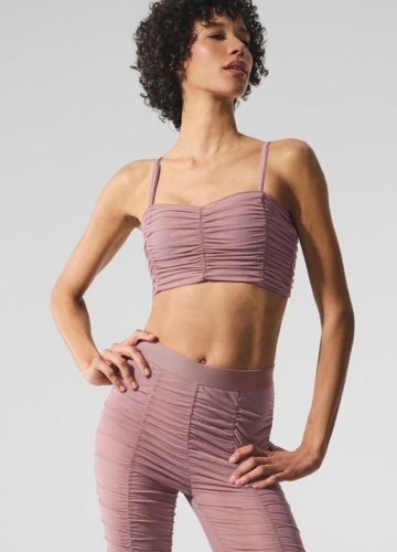 Model wearing a mauve-colored, ruched two-piece outfit consisting of a cropped top and high-waisted leggings.