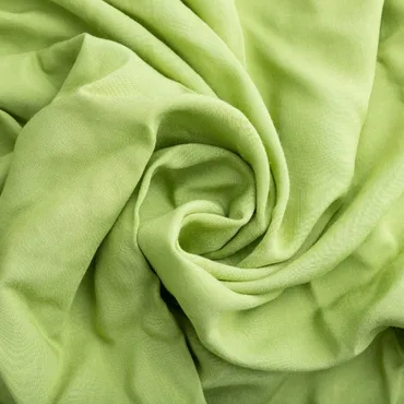 A close-up of soft, crumpled light green rayon fabric, showcasing its smooth texture and flow.