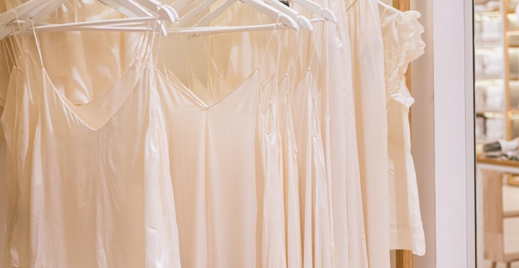A rack of light cream-colored dresses and tops, including several spaghetti-strap slips and a ruffled blouse, organized on white hangers. A pressing cloth is a reliable tool when using an iron to remove wrinkles from chiffon. As they say, “put an iron over a woman’s dress and she becomes dress’’—this should never happen. Using cotton as a barrier, such as placing it over a pillowcase, helps protect the fabric. The pressing cloth prevents direct heat from touching the chiffon while still allowing the material to stay flexible. This simple step can help remove wrinkles from chiffon safely, stopping any chance of burns or melting. remove wrinkles from chiffon