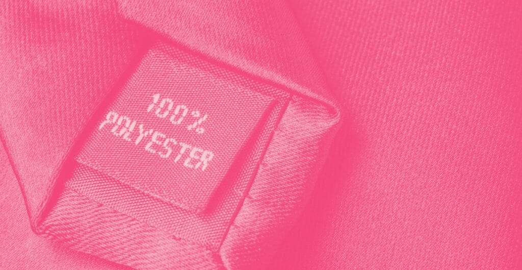 Close-up of a pink fabric label reading "HERSCHEL 100% POLYESTER" sewn onto a textured pink textile.