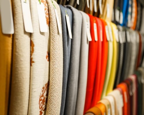 A close-up image of various fabric rolls hanging on a display rack, showcasing different colors, textures, and patterns.
