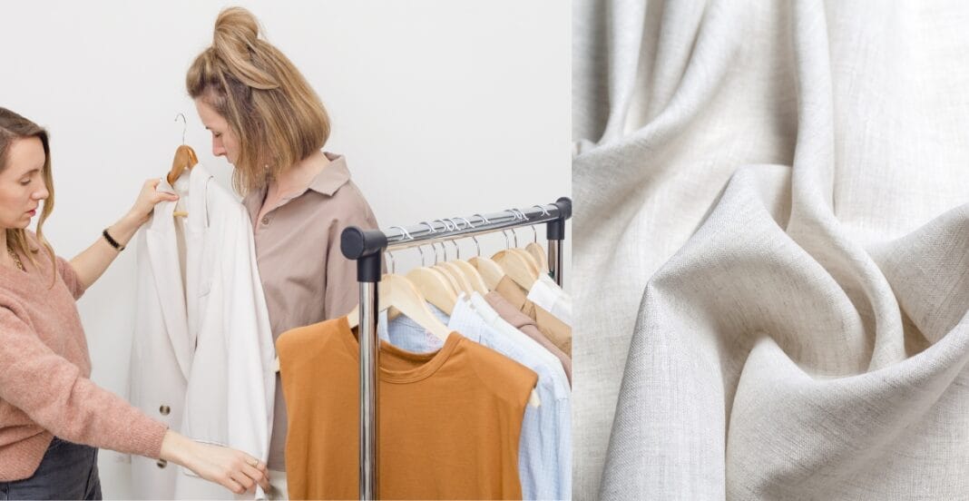 Two women selecting a white linen blazer from a clothing rack with various garments and linen fabric.
