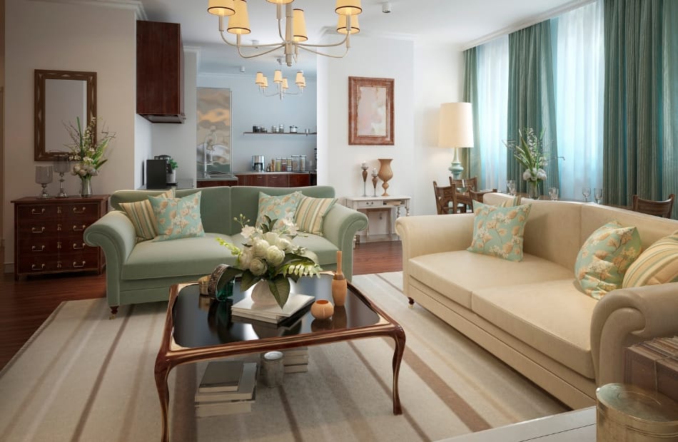 A spacious, elegant living room with pastel-colored sofas, a wooden coffee table, decorative pillows, vases with flowers, a large window with curtains, and ambient lighting.