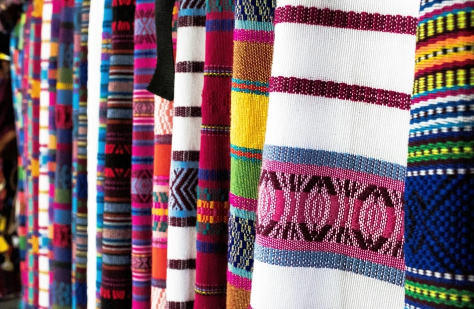 Close-up of colorful, woven textile fabrics with various intricate patterns hanging side by side.