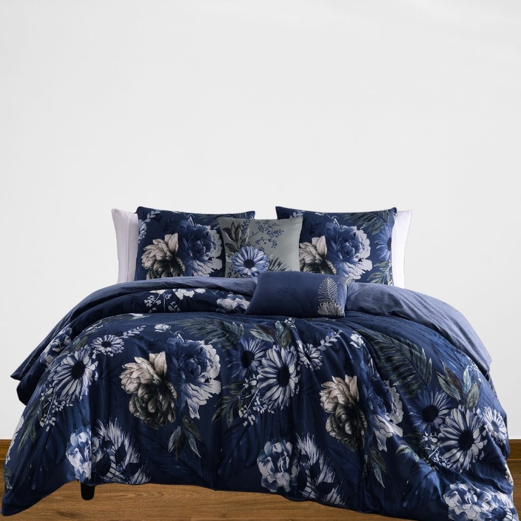 A neatly made bed with dark blue floral bedding and pillows, set against a plain white wall.