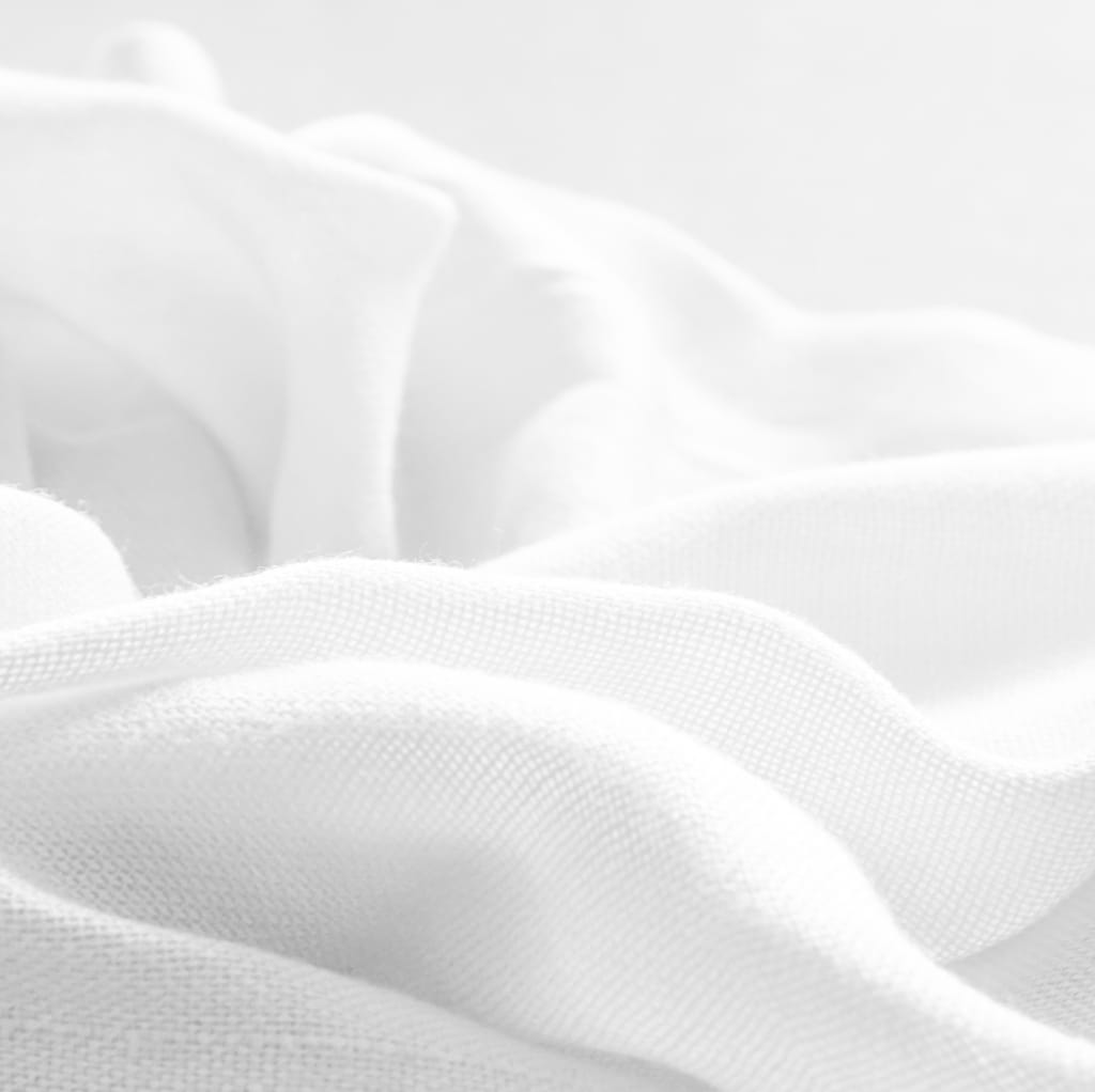Close-up of soft, white cotton fabric with a smooth, lightweight texture, slightly wrinkled.