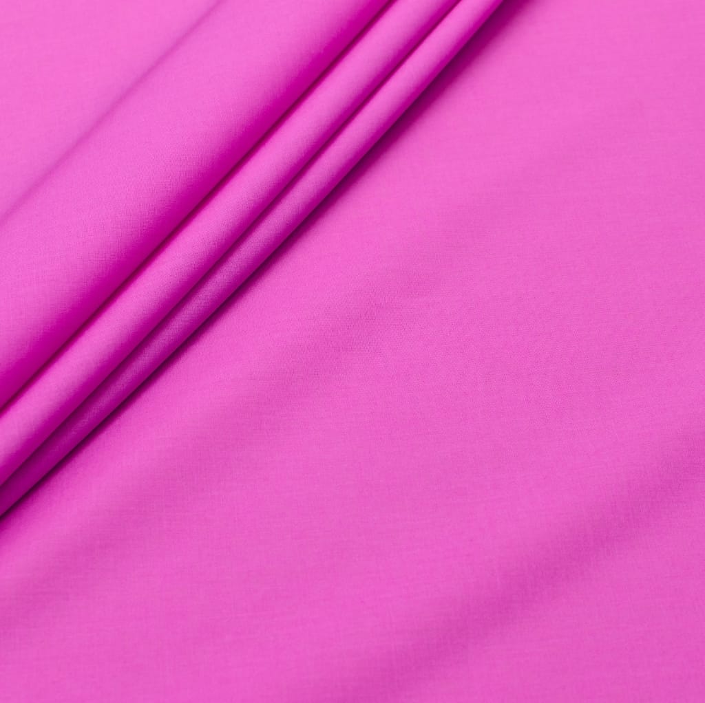 Close-up of bright pink cotton batiste fabric with gentle folds.
