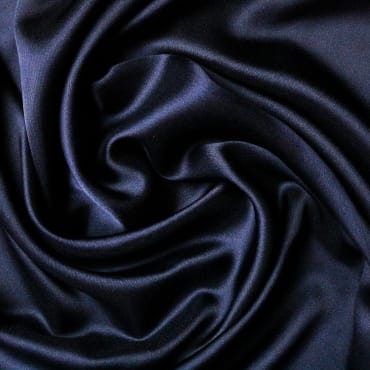 Close-up of smooth, shiny black polyester fabric with soft folds and a silky appearance.