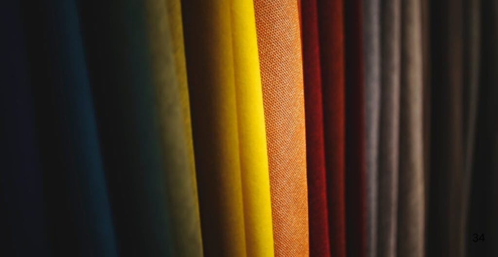Close-up of vertically arranged colorful fabric swatches, primarily in shades of yellow, orange, red, and neutral tones.