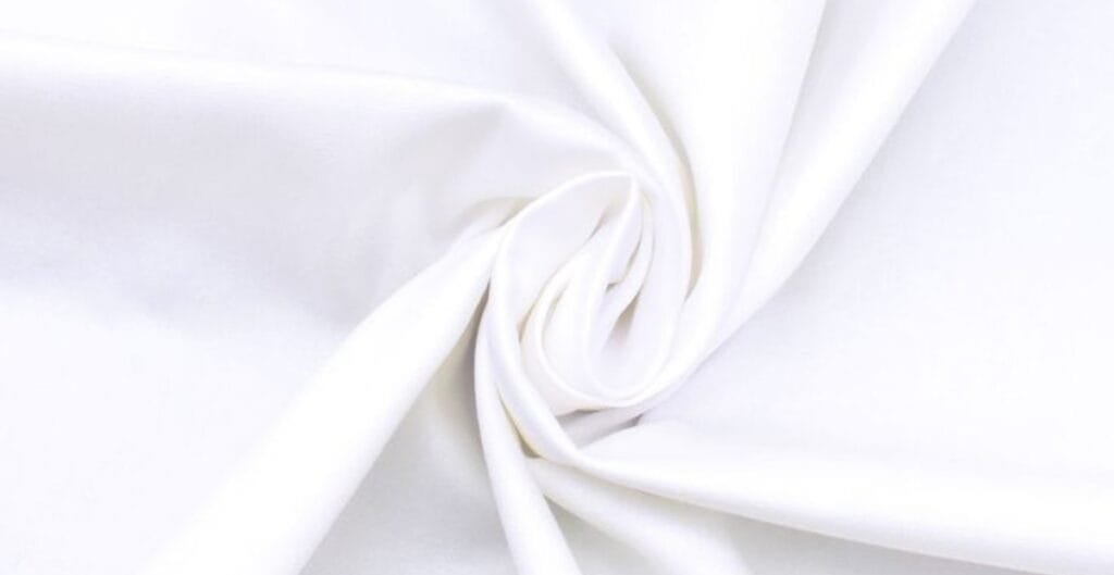 Close-up of smooth, white cotton fabric gathered and twisted.