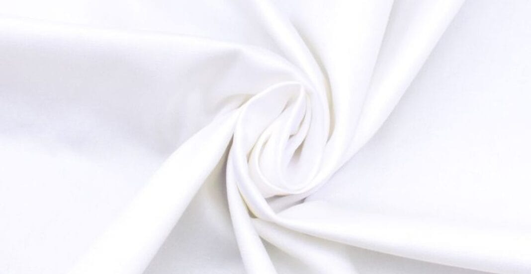 Close-up of smooth, white cotton fabric gathered and twisted.