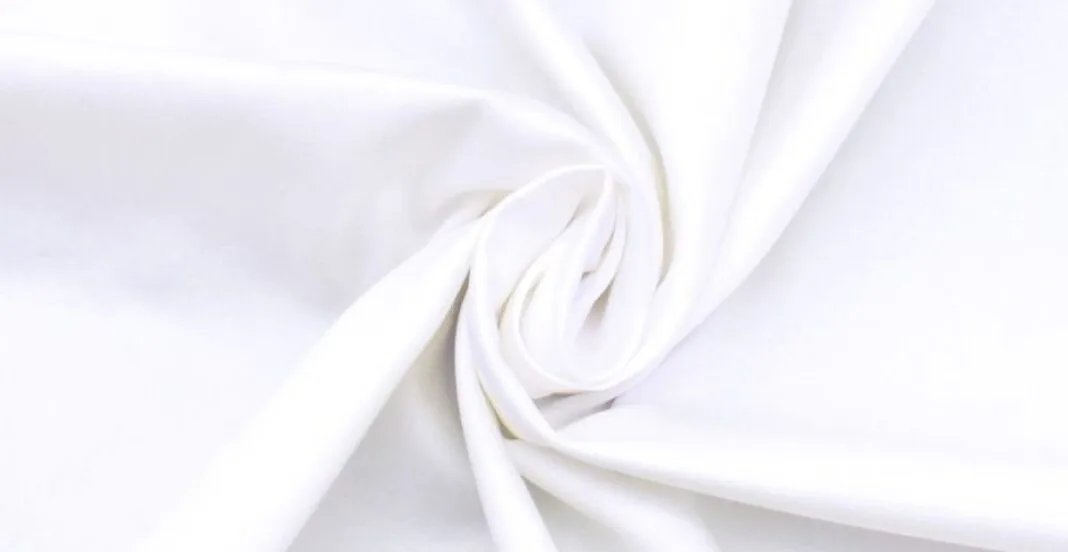 Close-up of smooth, white cotton fabric gathered and twisted.