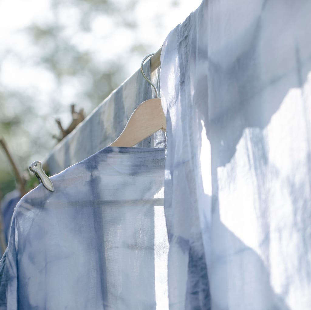 Close-up view of a light blue cotton fabric hanging on a clothesline, illuminated by sunlight.