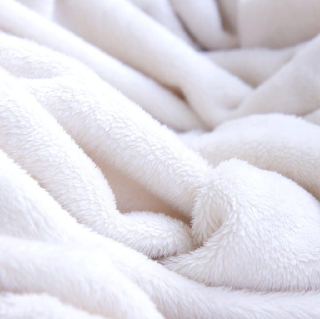Close-up of soft, fluffy white cotton fabric with a plush, cozy appearance, draped in gentle folds.