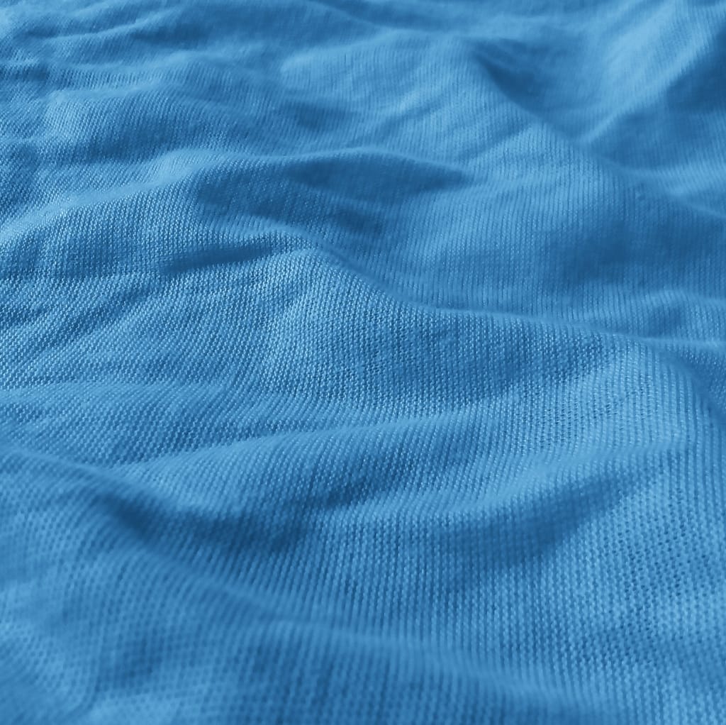 Close-up of a blue cotton fabric featuring a tightly woven, non-stretchy texture with slight wrinkles.
