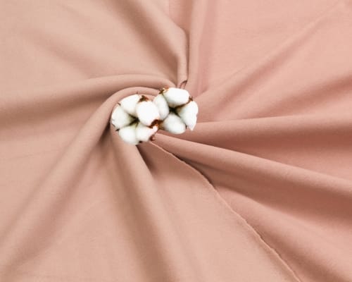 Close-up image of a pink fabric gathered at the center with a cluster of cotton bolls, showing the texture and softness of the material.