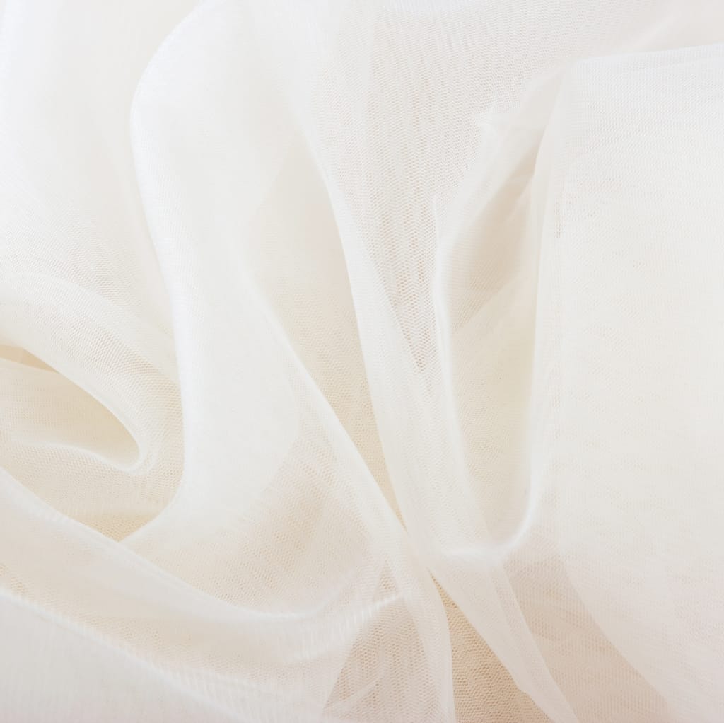 Close-up image of lightweight, sheer, white fabric with soft folds, suitable for summer clothing.