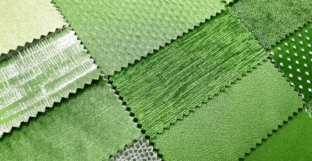 Various shades of green fabric swatches with different textures and patterns, arranged in overlapping layers.