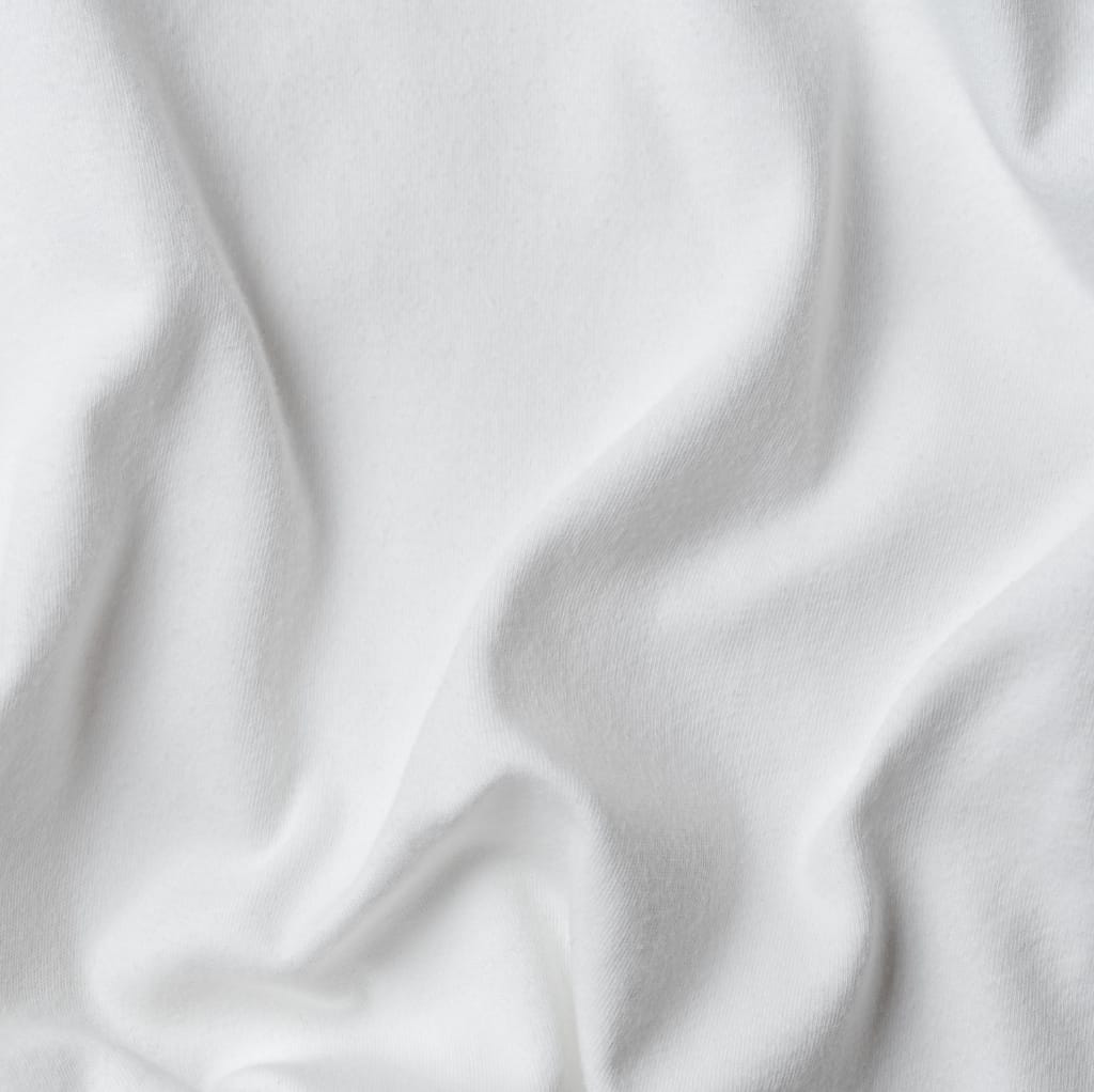 A close-up of soft, white fabric with gentle folds and a smooth, matte surface, indicating a luxurious textile material.