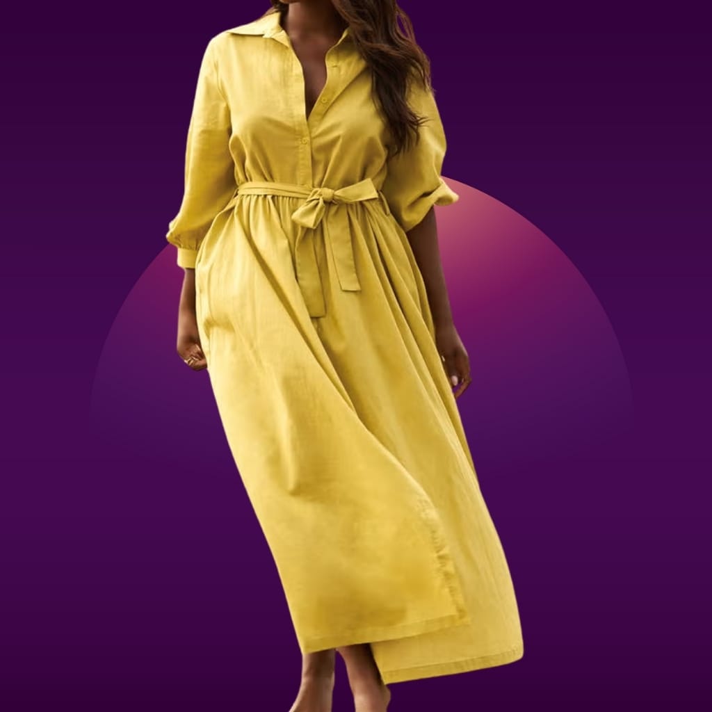 A woman wearing a yellow button-up dress with a tied waist, standing against a purple background.