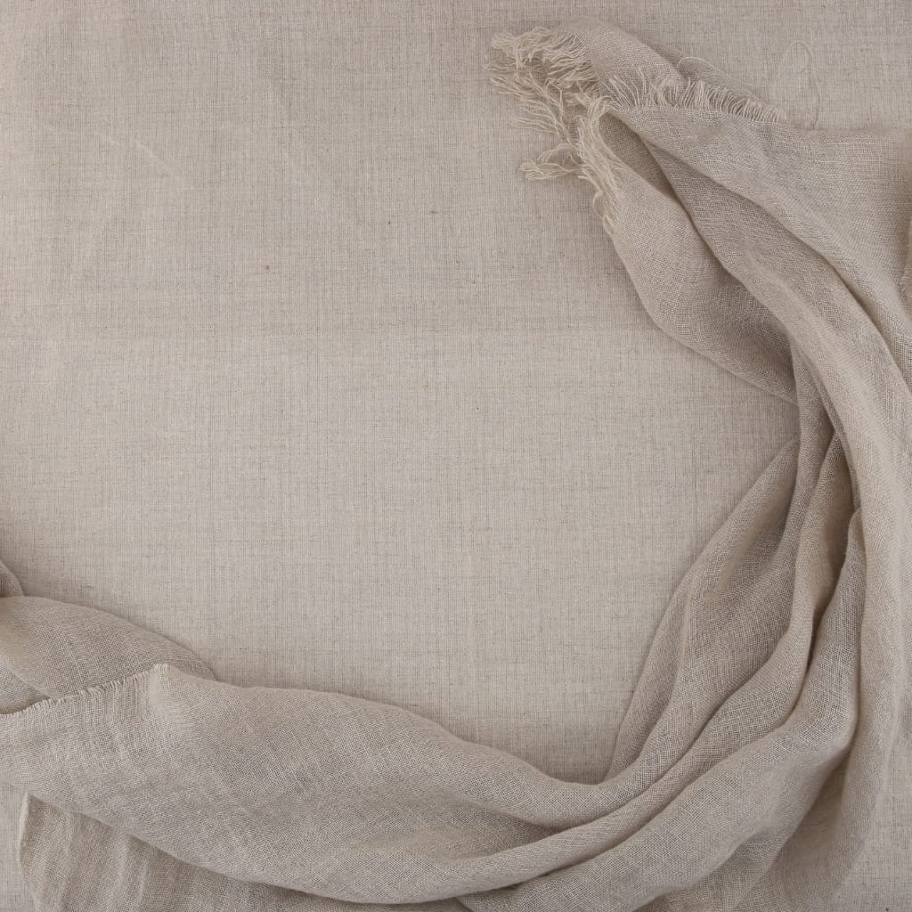 A flat, textured beige linen fabric with loosely draped, slightly frayed edges on the top and bottom, creating a soft, elegant background.