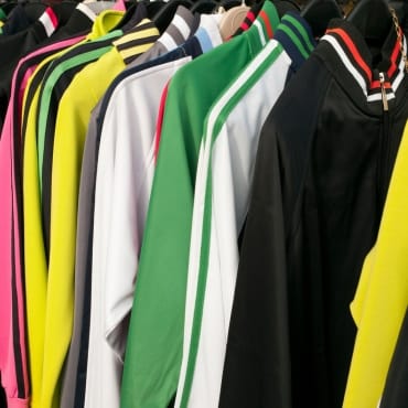 Rows of colorful sports jackets and track suits made of polyester hanging on a rack.