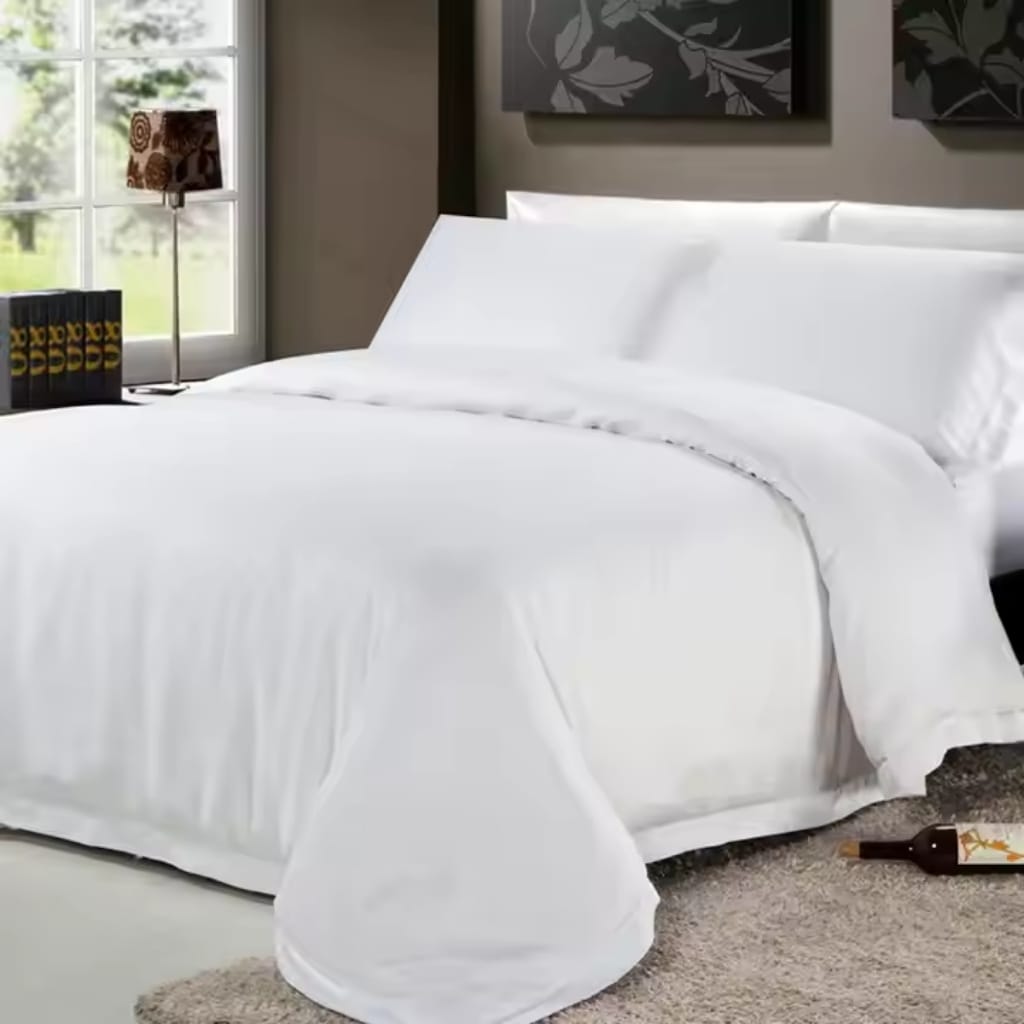 A neatly made bed with pristine white sheets and pillowcases, positioned next to a window with a view of greenery outside. On the side table, there are several black books with yellow text, and a decorative lamp with a floral pattern lampshade. A bottle of wine lies on the beige carpet near the foot of the bed.