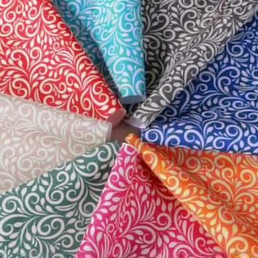 A colorful array of printed polyester fabric swatches arranged in a circular pattern, showcasing intricate swirling designs in various vibrant colors.