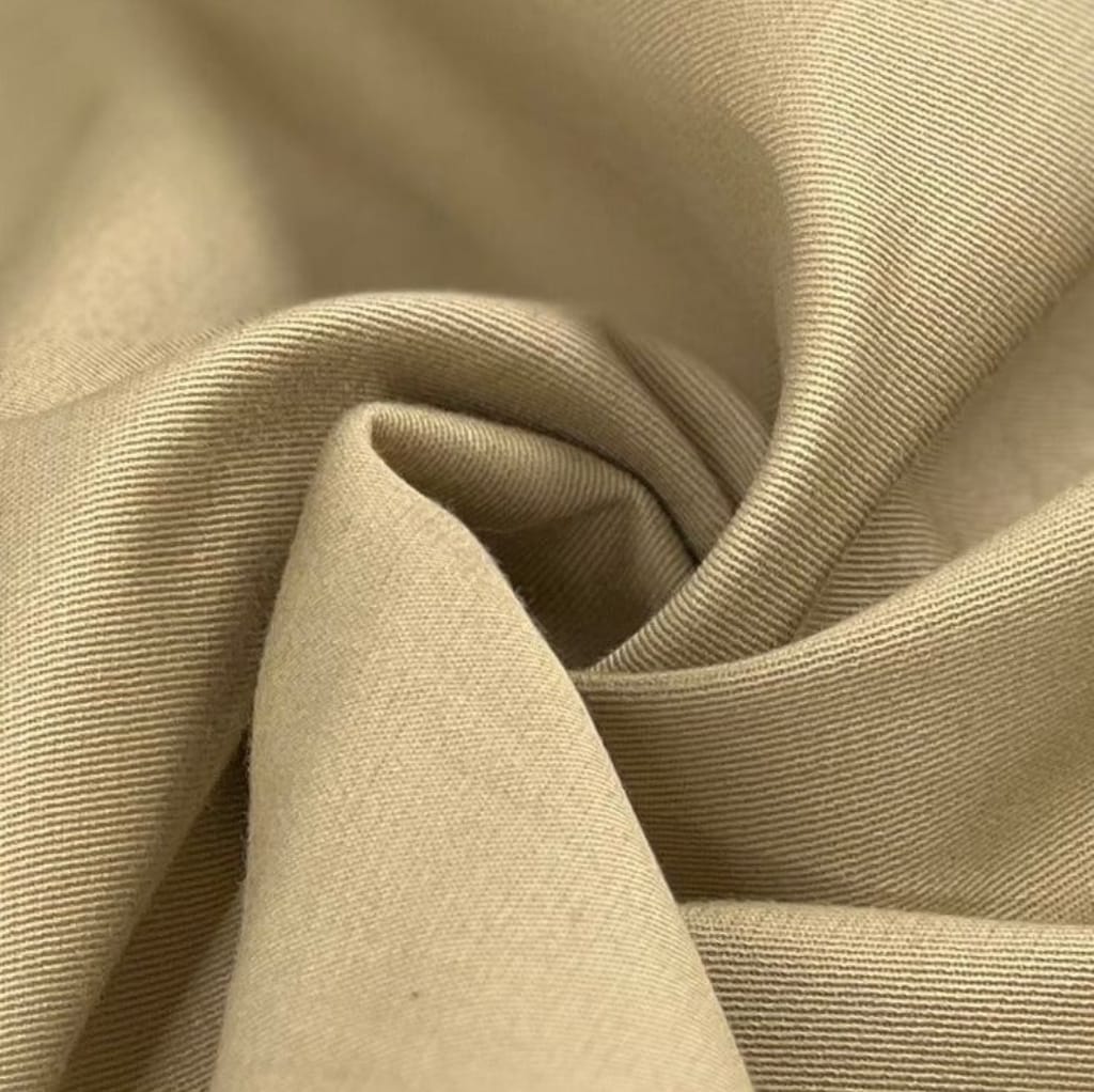 Close-up of beige twill cotton fabric, showcasing its diagonal weave pattern and smooth texture.