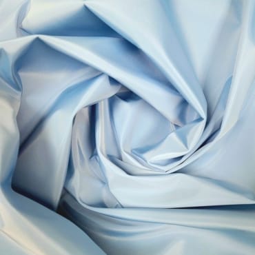 Close-up of light blue polyester fabric with a smooth, shiny, and slightly wrinkled surface.