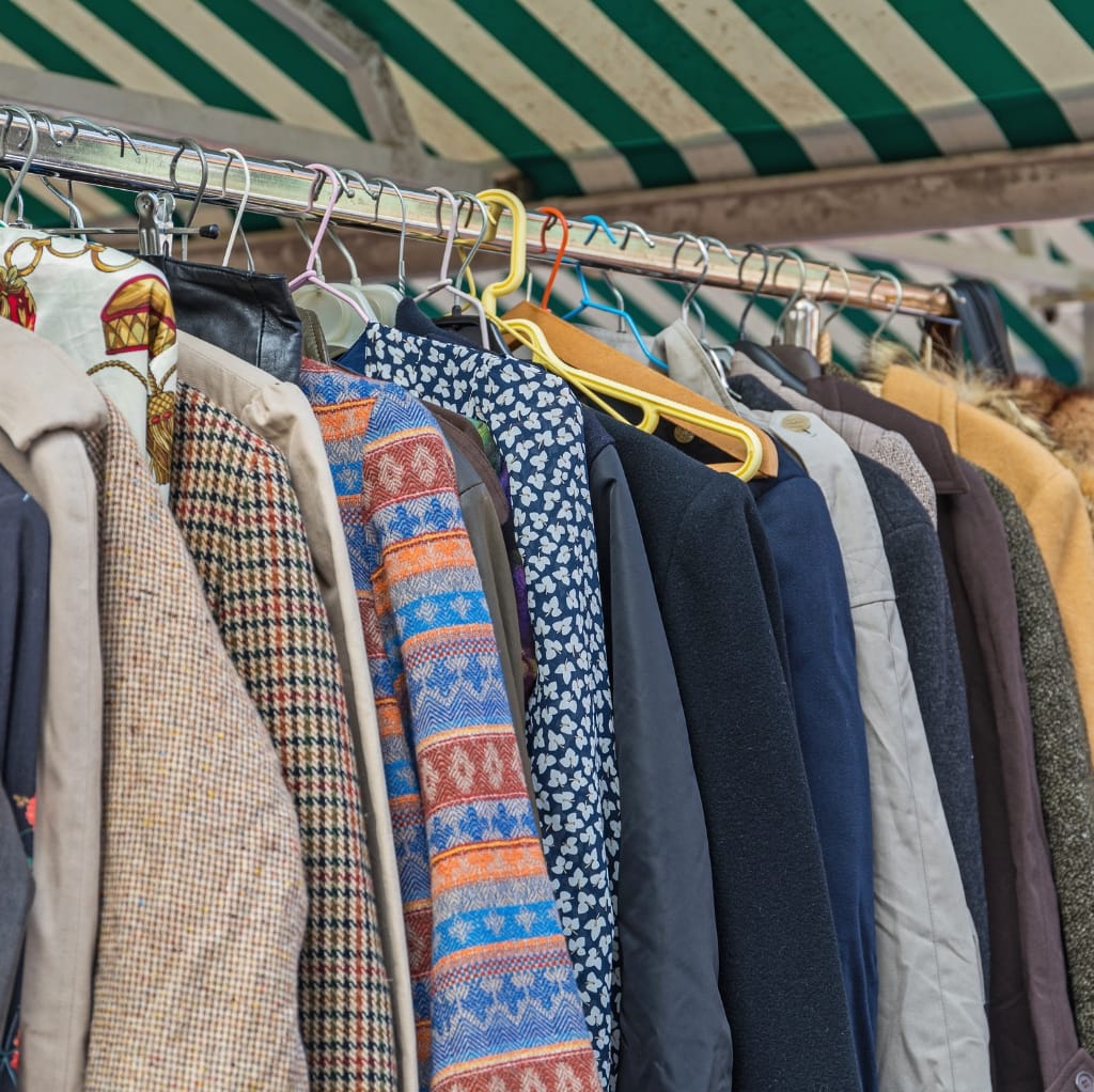 A row of men's jackets and coats hanging on a rack, showcasing a variety of fabrics and patterns suitable for layering with cotton apparel in winter.